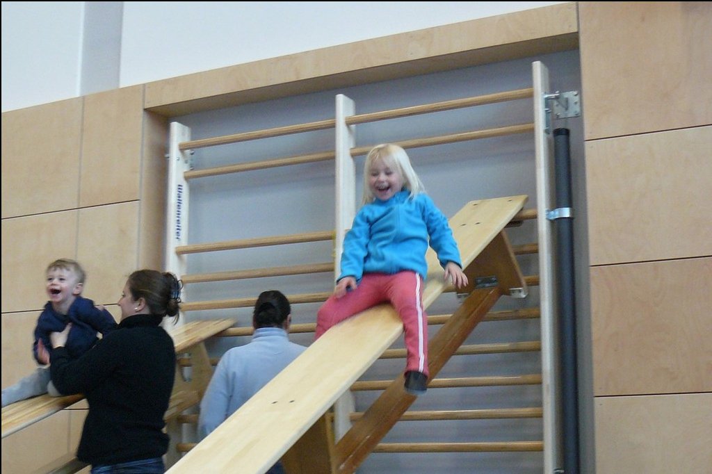 Kinder beim Eltern-Kind-Turnen auf der Rutsche in der Turnhalle